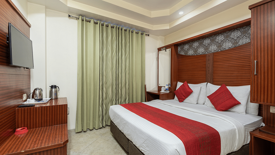 Side view of a deluxe room featuring a king size bed, a TV, and a tea & coffee maker on the table at DLS Hotels The Rock Castle.